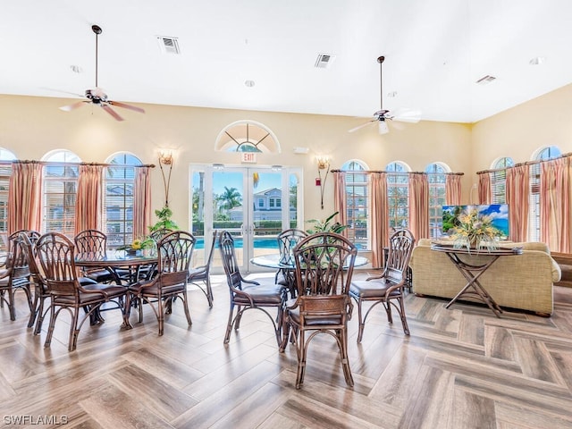 dining room featuring a towering ceiling, ceiling fan, and light parquet flooring