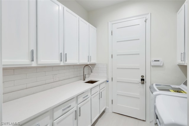 clothes washing area featuring sink, cabinets, and washer and clothes dryer