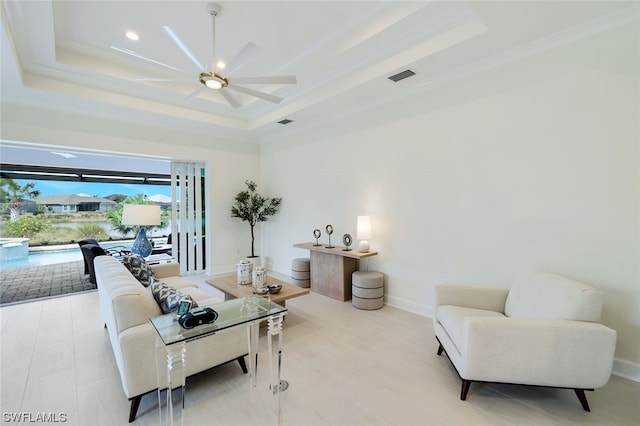 living room with ceiling fan and a raised ceiling