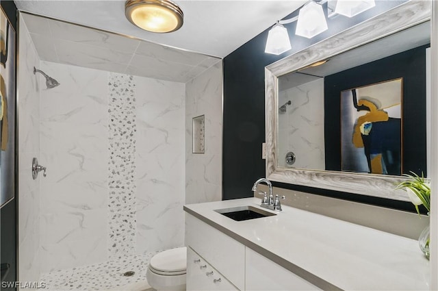 bathroom with toilet, tiled shower, and vanity