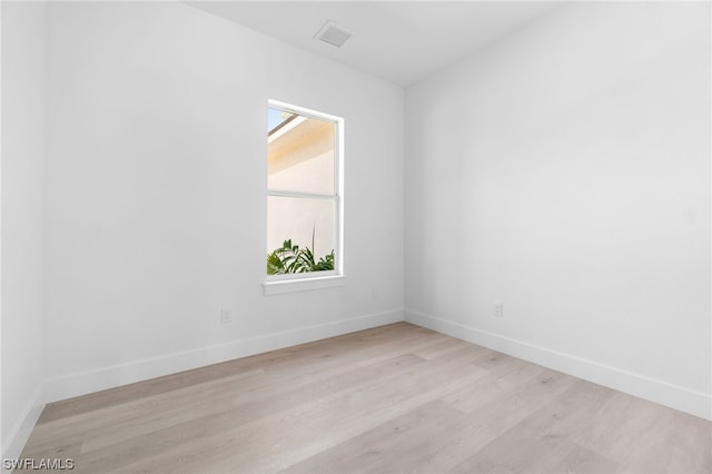 spare room with light wood finished floors, visible vents, and baseboards