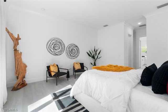 bedroom with ornamental molding, visible vents, and wood finished floors