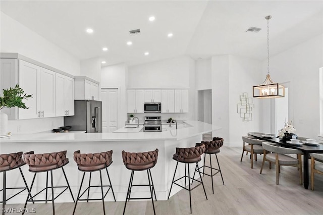 kitchen featuring stainless steel appliances, visible vents, a sink, and a peninsula