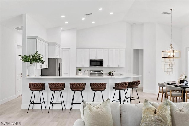 kitchen with appliances with stainless steel finishes, open floor plan, visible vents, and a kitchen breakfast bar