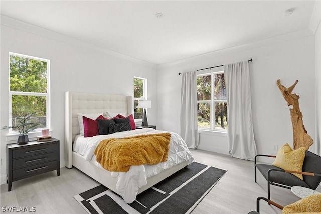 bedroom with crown molding and light wood finished floors