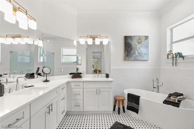 full bath with double vanity, a soaking tub, a sink, and tile walls