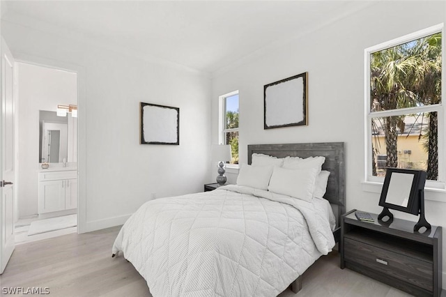 bedroom featuring baseboards, connected bathroom, and light wood-style floors