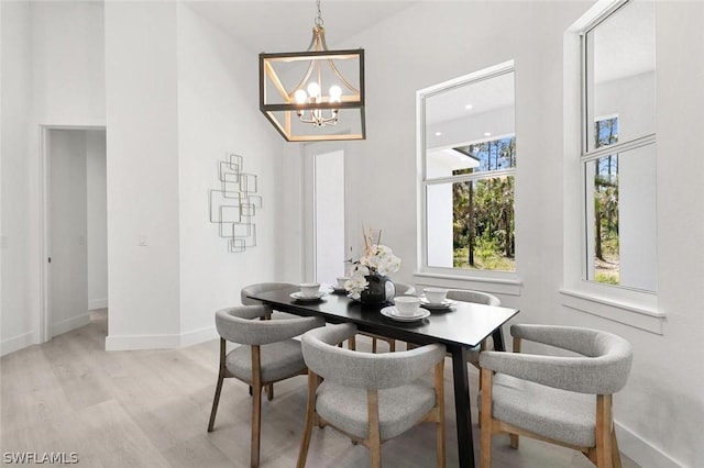 dining area with light wood-type flooring, baseboards, and a notable chandelier