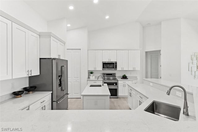 kitchen featuring stainless steel appliances, an island with sink, a sink, and white cabinets