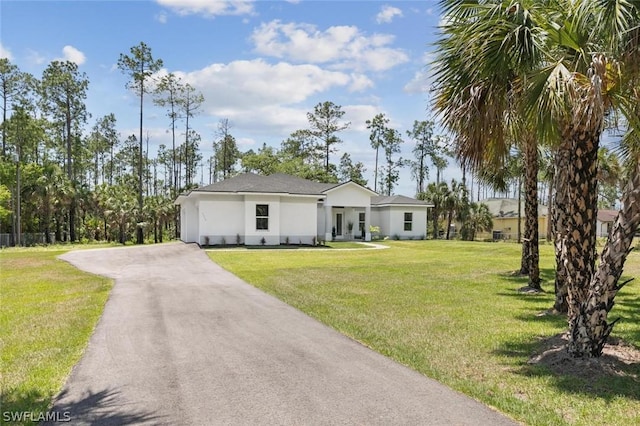 view of front of house featuring aphalt driveway, a front yard, and stucco siding