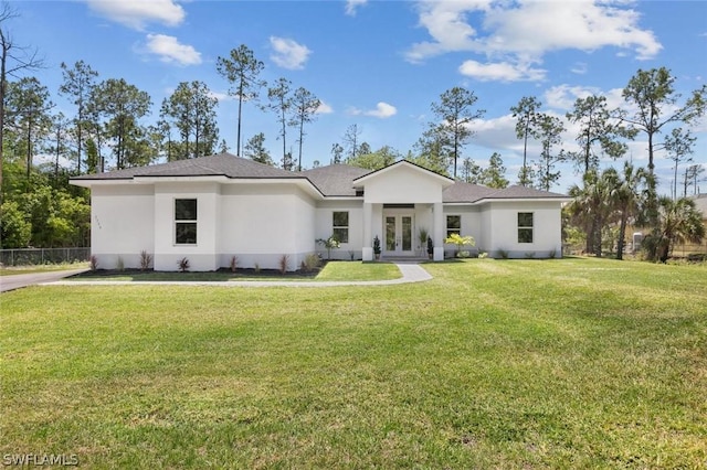 view of front facade with stucco siding, a front lawn, and french doors