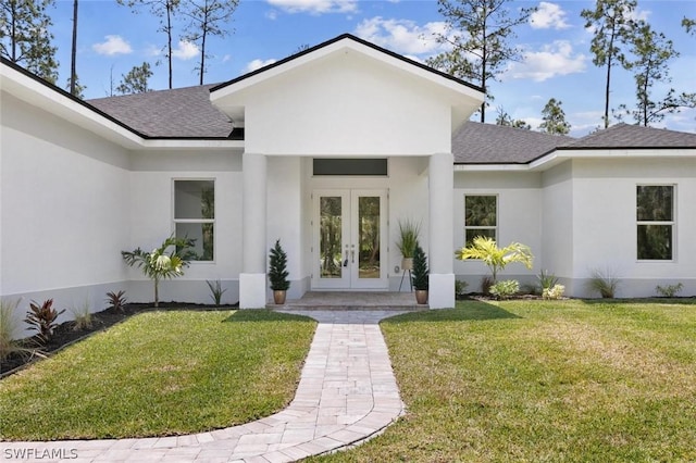 view of exterior entry with roof with shingles, french doors, a lawn, and stucco siding