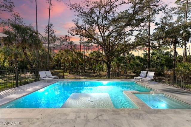 pool at dusk with a fenced in pool and fence