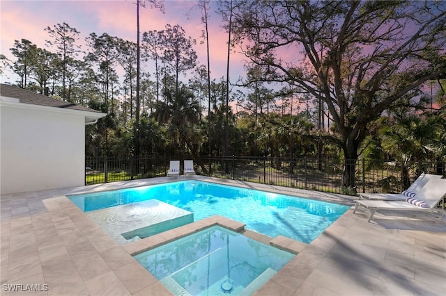 view of swimming pool with a patio area, a pool with connected hot tub, and fence