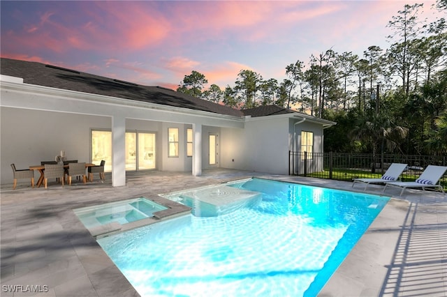 view of swimming pool featuring a patio area, a pool with connected hot tub, and fence