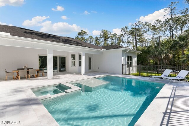 view of pool with a pool with connected hot tub, fence, and a patio