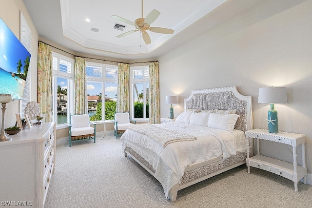 bedroom with light carpet, a tray ceiling, and ceiling fan