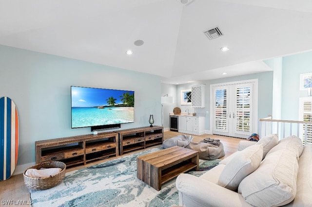 living room featuring high vaulted ceiling, french doors, beverage cooler, light wood-type flooring, and sink