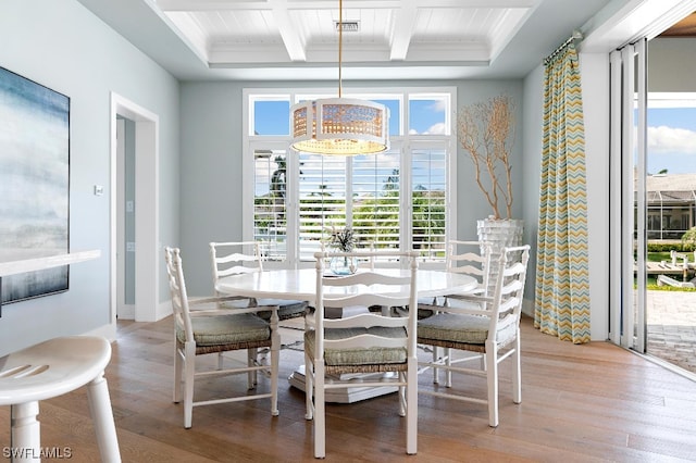 dining room with plenty of natural light, beamed ceiling, coffered ceiling, and light hardwood / wood-style flooring