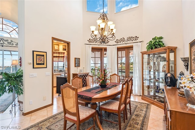 tiled dining space with a high ceiling, a chandelier, and french doors