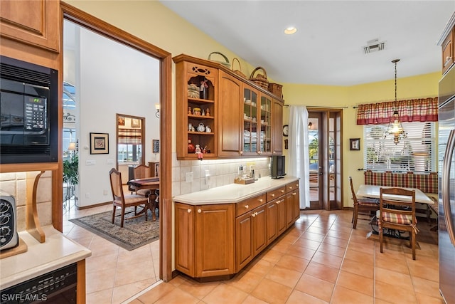 kitchen with a chandelier, decorative light fixtures, light tile floors, black microwave, and tasteful backsplash