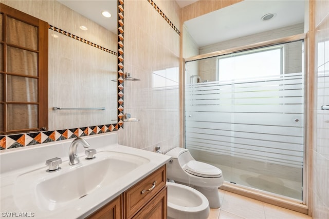 bathroom featuring tile walls, tile flooring, toilet, a bidet, and oversized vanity