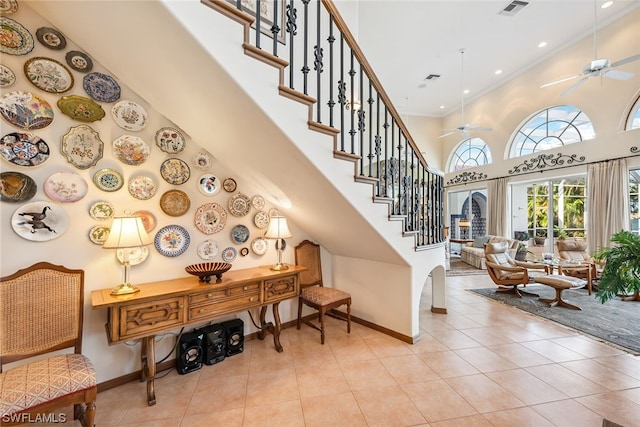 interior space featuring light tile floors, french doors, ceiling fan, and a towering ceiling