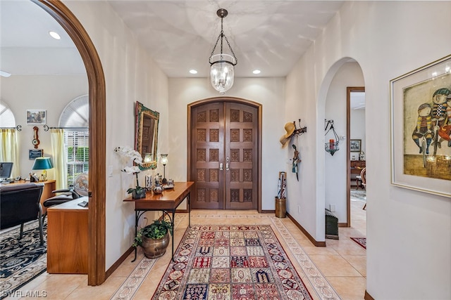 foyer entrance with light tile floors and an inviting chandelier