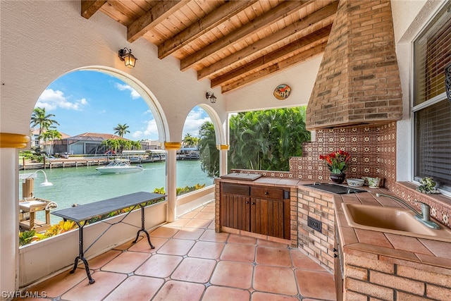 view of terrace featuring area for grilling, a water view, and sink