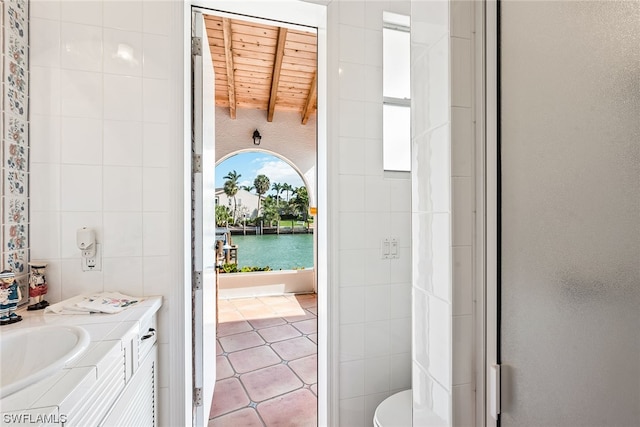 bathroom featuring toilet, vanity, wood ceiling, tile walls, and tile flooring