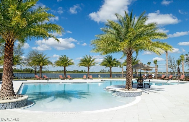 view of pool featuring a water view and a patio