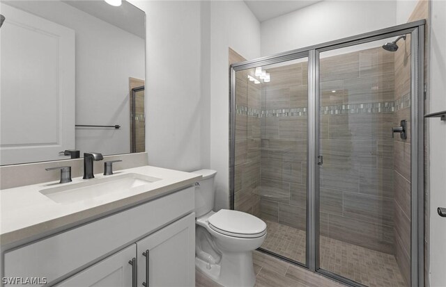 bathroom featuring vanity, hardwood / wood-style floors, toilet, and walk in shower