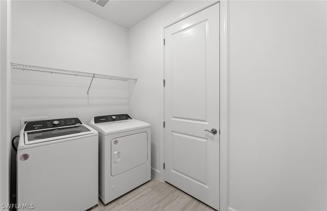 washroom with separate washer and dryer and light wood-type flooring