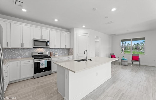 kitchen featuring sink, stainless steel appliances, an island with sink, and white cabinets