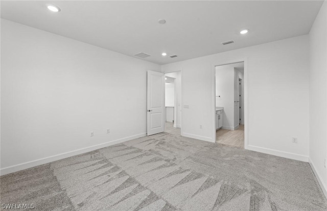 unfurnished bedroom featuring ensuite bathroom and light carpet