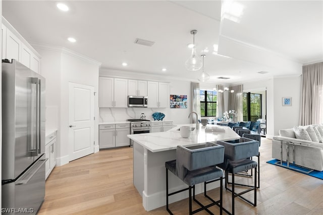 kitchen featuring pendant lighting, stainless steel appliances, light hardwood / wood-style flooring, white cabinetry, and a breakfast bar area