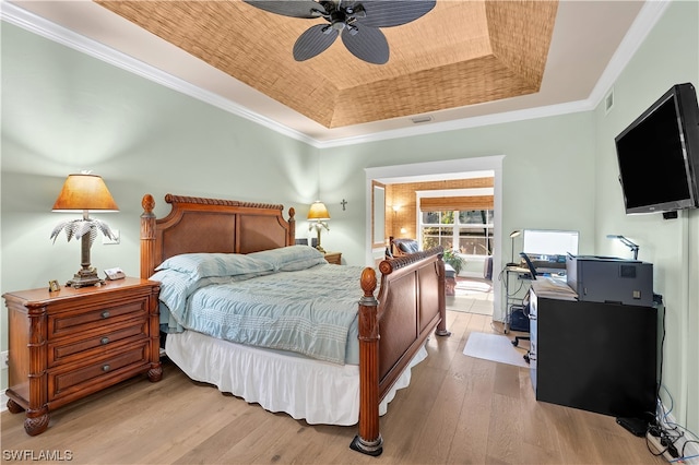 bedroom with light hardwood / wood-style floors, a raised ceiling, ceiling fan, and ornamental molding