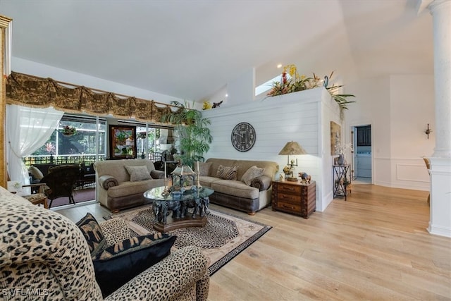 living room featuring light hardwood / wood-style floors, ornate columns, and high vaulted ceiling