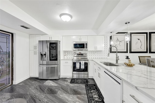 kitchen featuring a sink, light stone counters, backsplash, white cabinetry, and appliances with stainless steel finishes