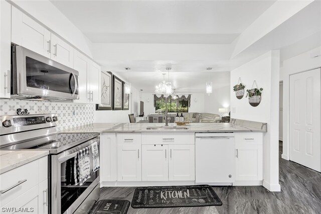 kitchen featuring light stone countertops, sink, stainless steel appliances, kitchen peninsula, and white cabinets