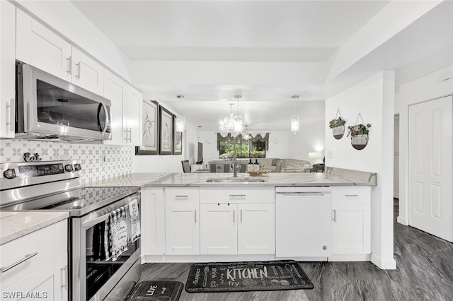 kitchen with light stone countertops, a sink, decorative backsplash, white cabinets, and appliances with stainless steel finishes