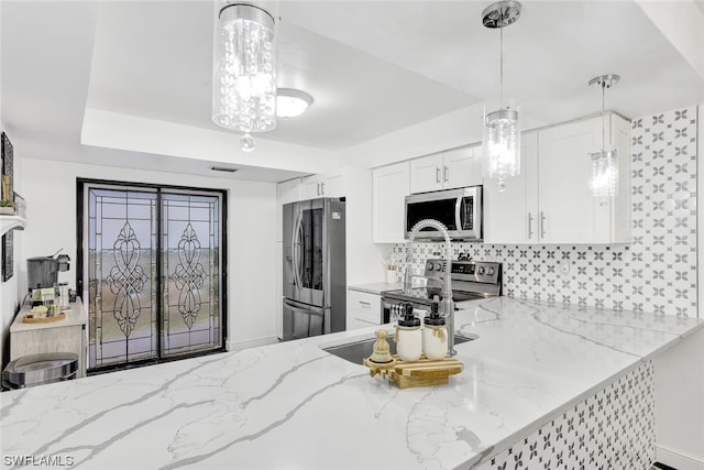 kitchen featuring light stone countertops, hanging light fixtures, white cabinets, appliances with stainless steel finishes, and backsplash