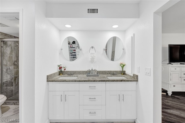 bathroom with double vanity, a shower stall, and a sink