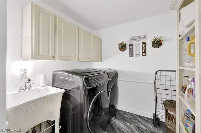 laundry area with a sink, cabinet space, wainscoting, and washing machine and clothes dryer