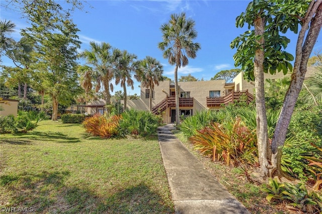 view of front of house featuring a front yard, stairway, and stucco siding