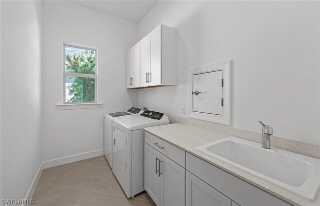 washroom featuring sink, light tile patterned flooring, cabinets, and independent washer and dryer