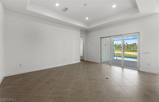 tiled spare room with a tray ceiling and ornamental molding