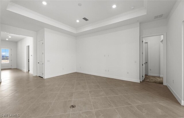 tiled spare room featuring a raised ceiling and crown molding