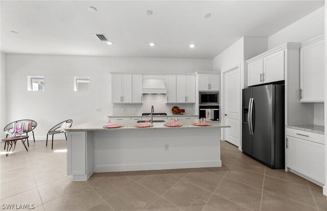 kitchen with white cabinetry, premium range hood, stainless steel appliances, and an island with sink