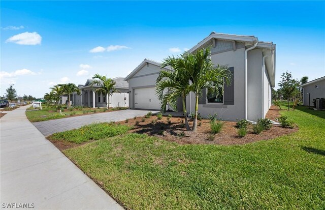 view of front of home with central AC, a garage, and a front lawn